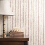 Decorative wallpaper with a subtle pattern, a lamp, and books on a wooden surface.