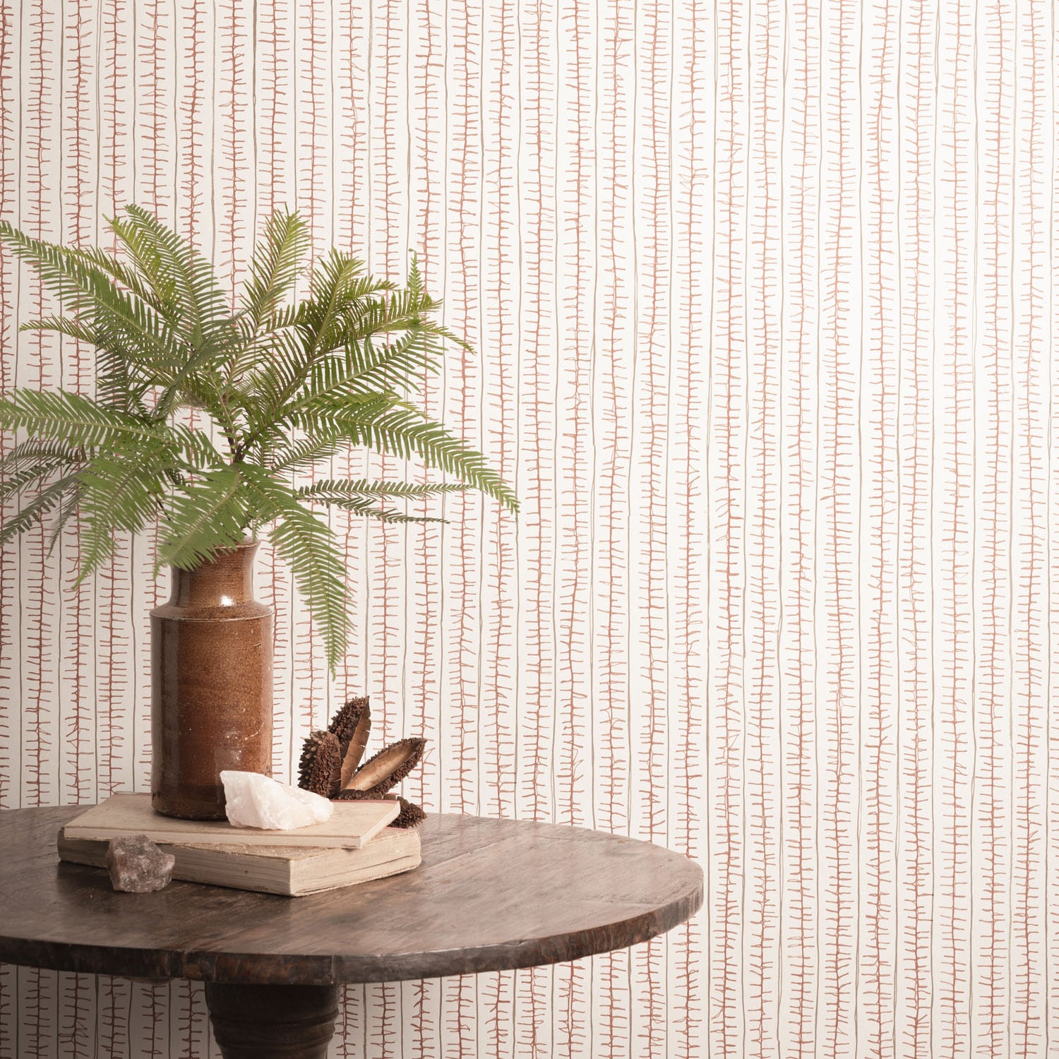 Decorative table with a plant and books against a striped wallpaper. 