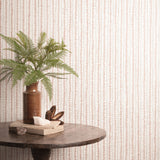 Decorative table with a plant and books against a striped wallpaper. 