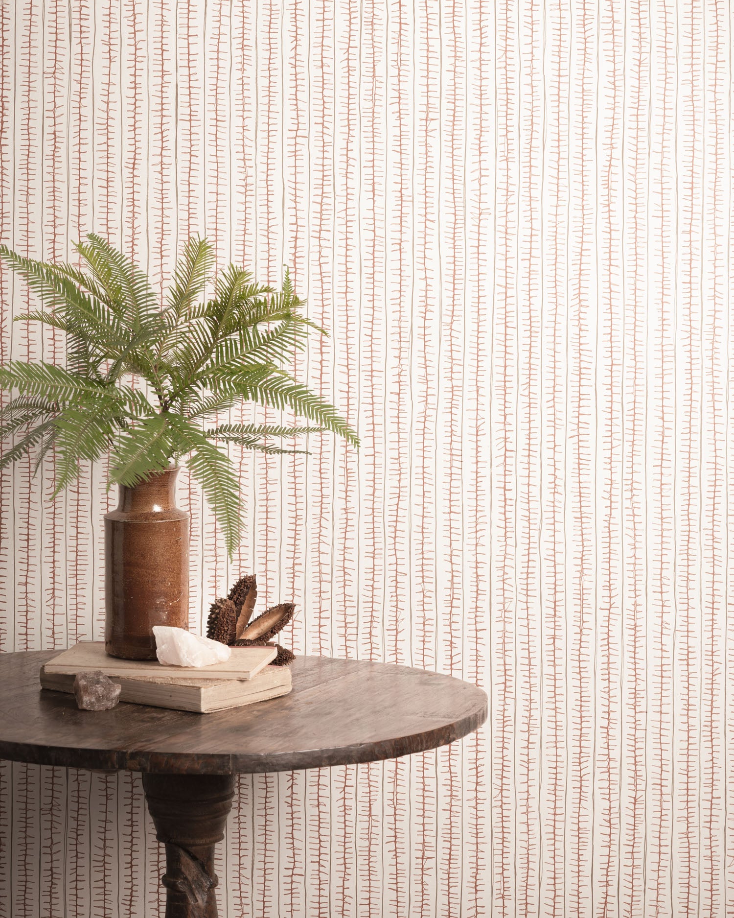 Decorative table with a plant and books against a striped wallpaper. 