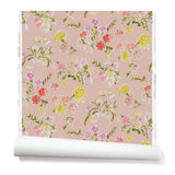 Partially unrolled wallpaper with a pattern of large-scale line-drawn flowers in gray ink with red, pink and yellow watercolors, on a pink background.