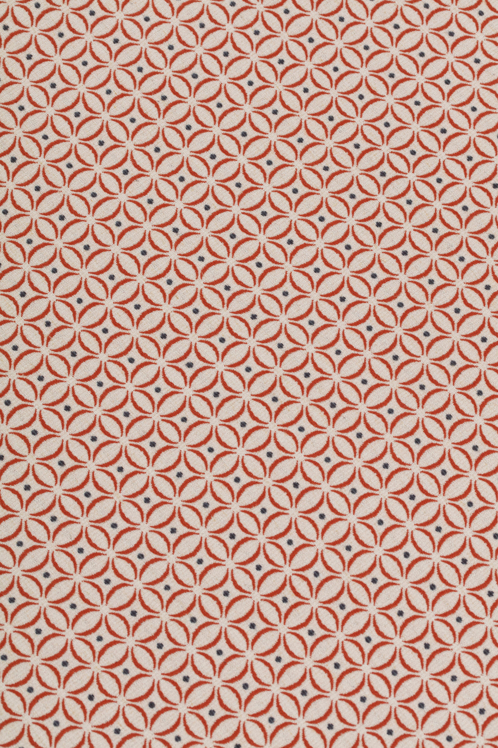 Detail of woven fabric in a geometric grid print in red and navy on a cream field.