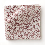 Fabric swatch with small scale coral design in wine red on white. 