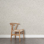 Wooden chair against a patterned grey watercolor wallpaper wall