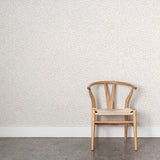 Wooden chair against a light gray watercolor wallpaper. 