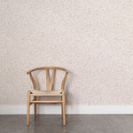Wooden chair against a coral watercolor wallpaper. 
