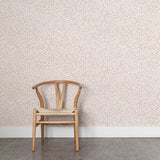 Wooden chair against a coral watercolor wallpaper. 