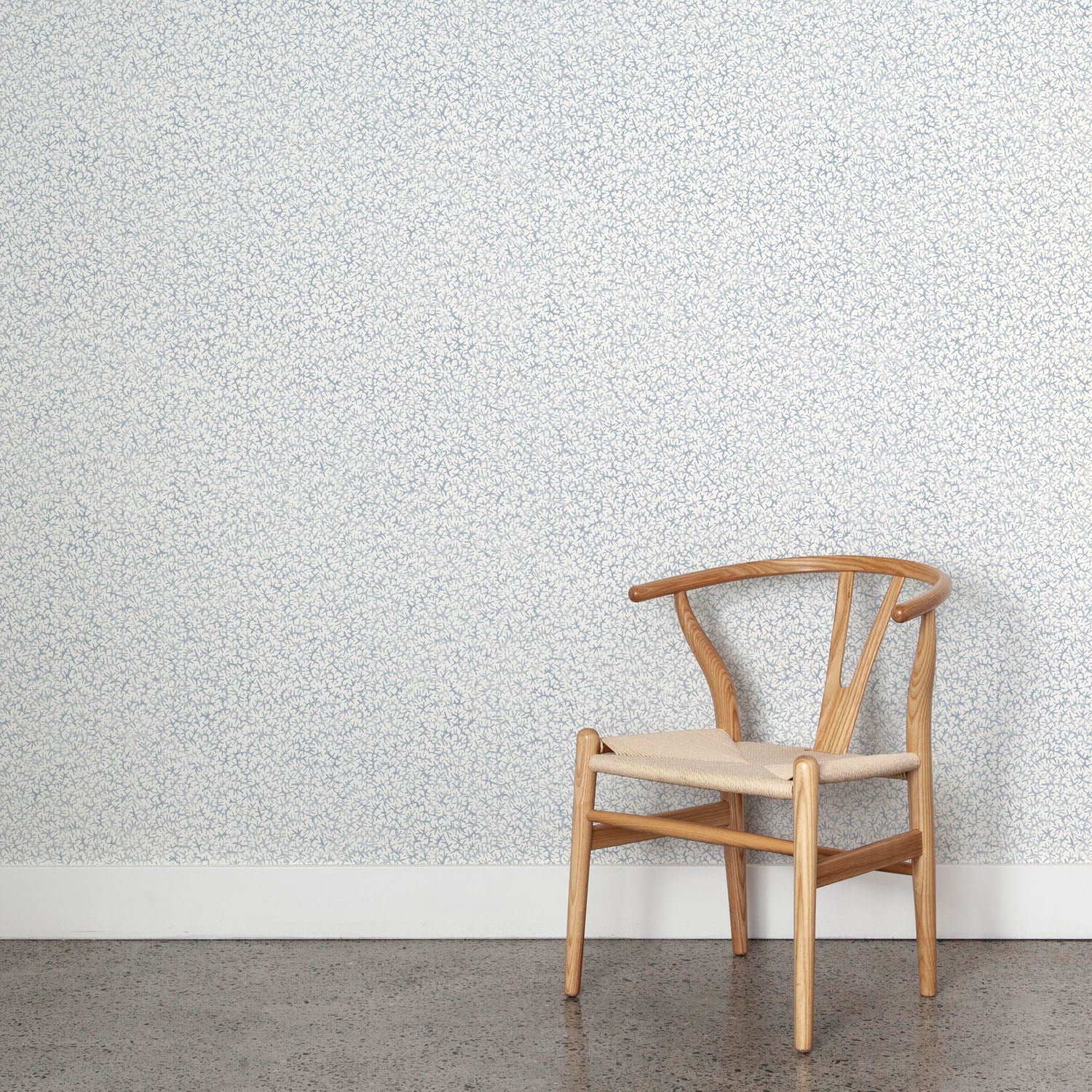 Wooden chair against a patterned pastel blue wallpaper wall