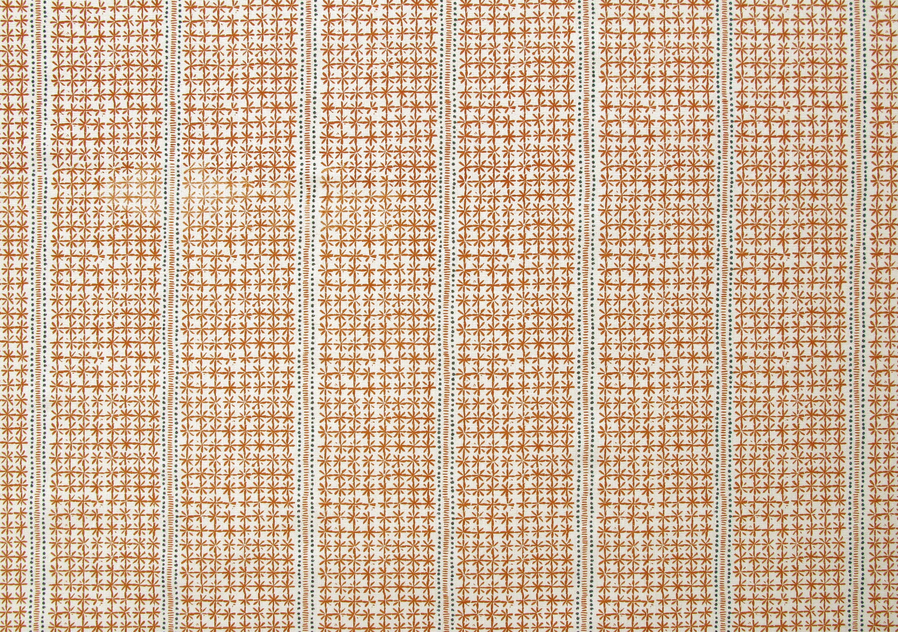 Detail of fabric in a dense repeating stripe and star print in burnt orange on a cream field.