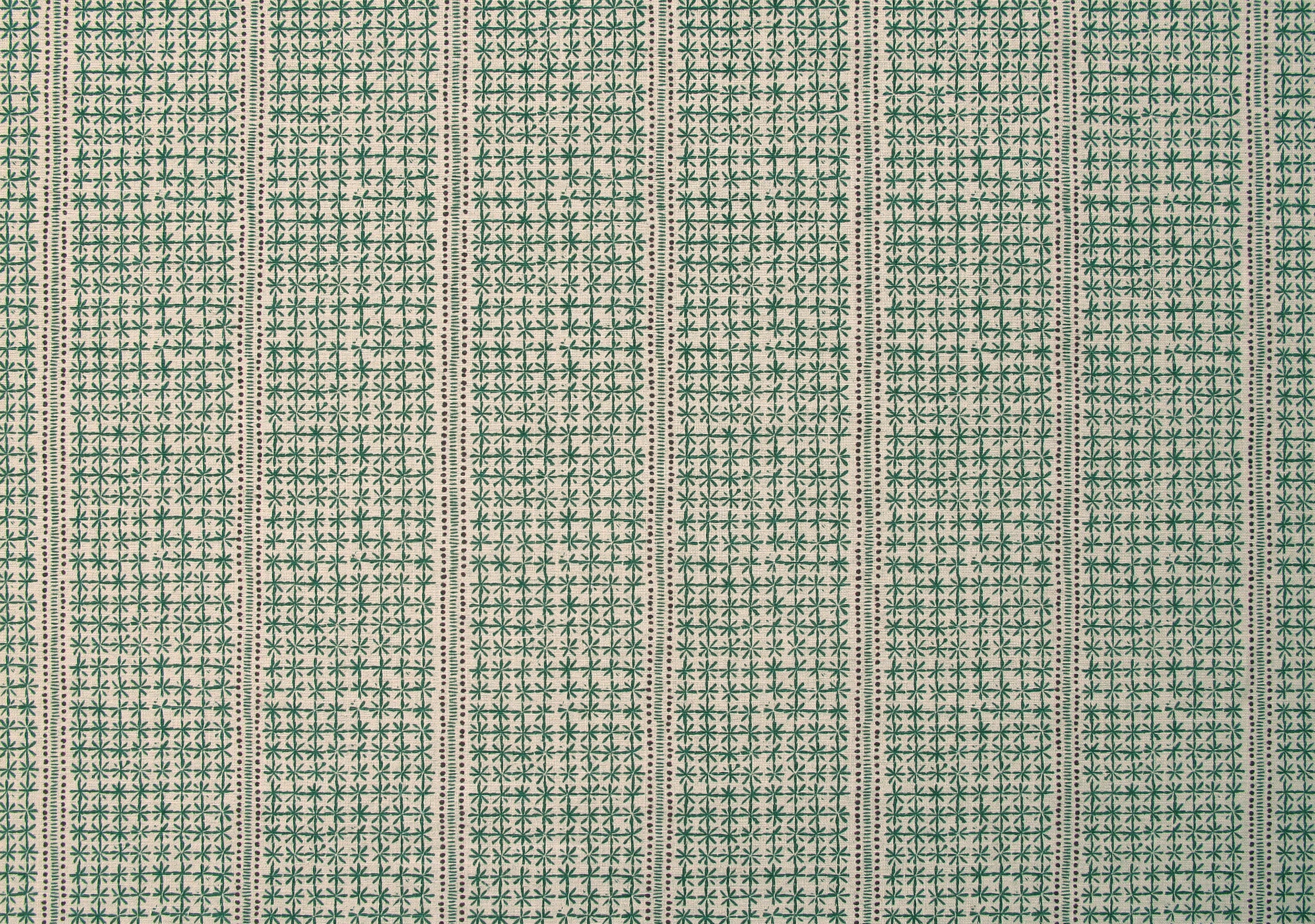 Detail of fabric in a dense repeating stripe and star print in green on a tan field.