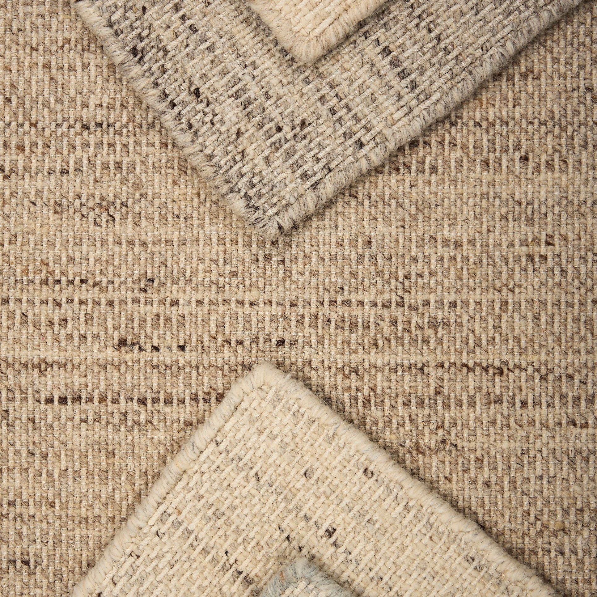 Stack of strié textural broadloom carpet in a range of neutral tones.