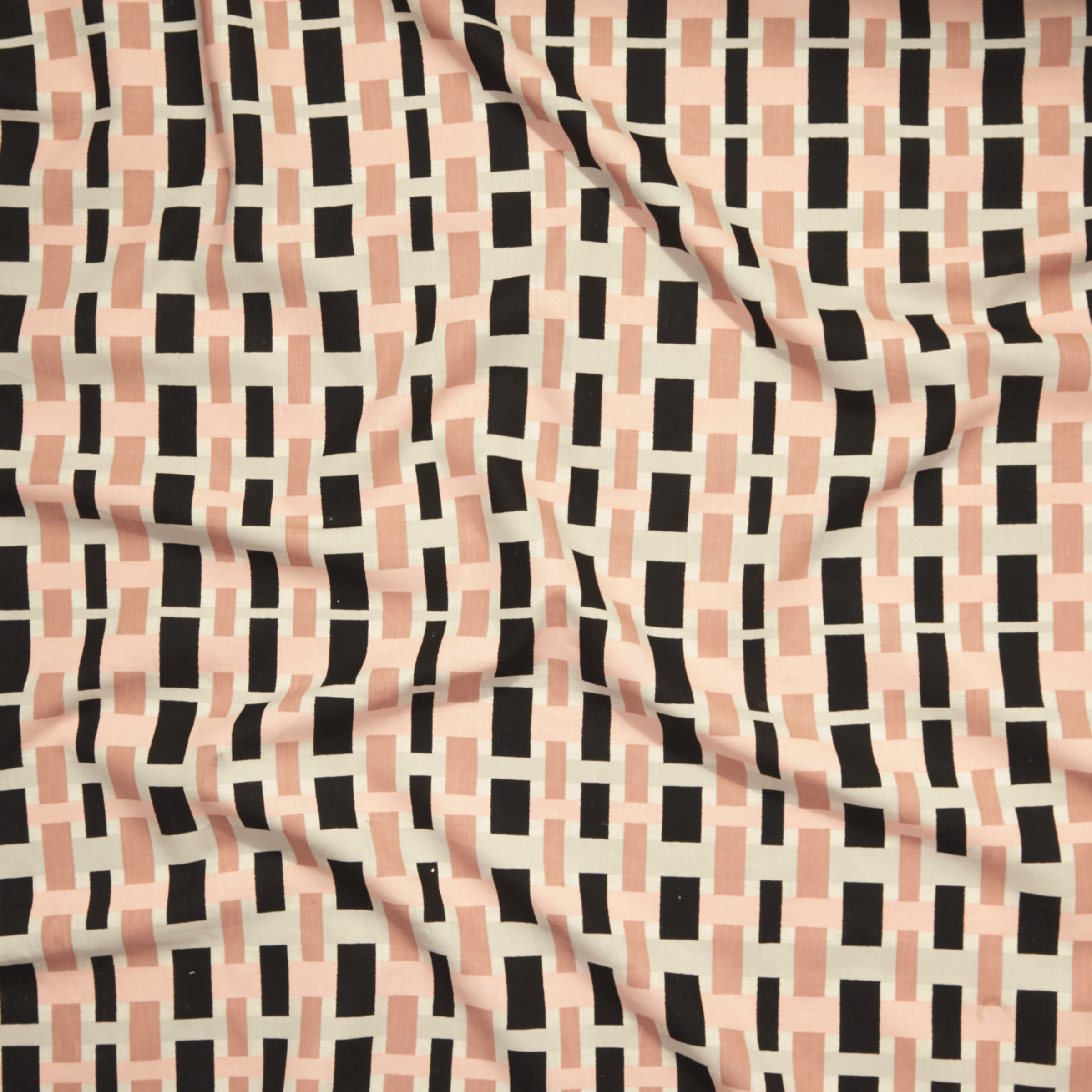 Close up of printed linen with graphic plaid pattern in shades of pink, beige and black.