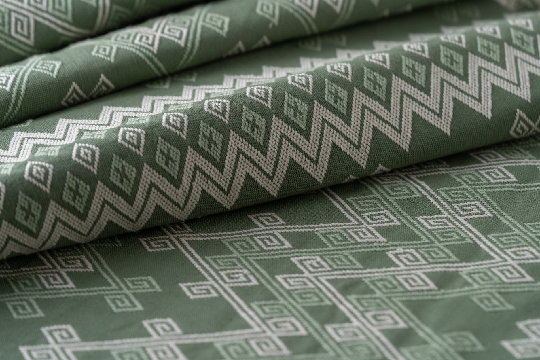 Green fabric with geometric pattern, lightly folded.
