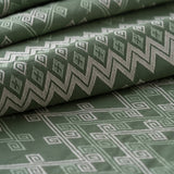 Green fabric with geometric pattern, lightly folded.