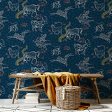 A bench and basket stand in front of a wall papered in a playful hand-drawn animal print in shades of white, pink and navy.