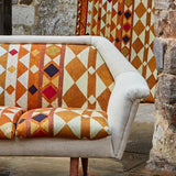 A couch upholstered in a global geometric print in shades of orange, yellow, brown and red.