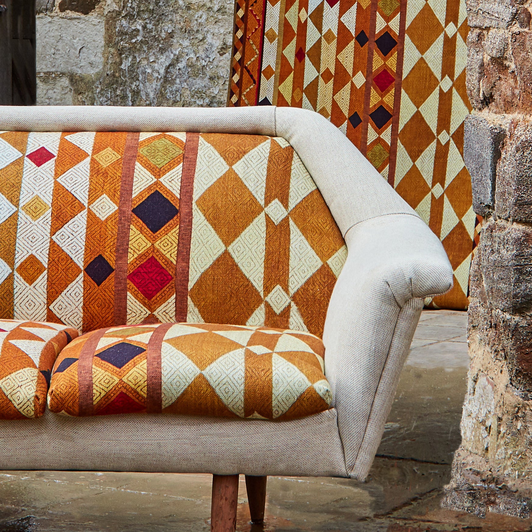 A couch upholstered in a global geometric print in shades of orange, yellow, brown and red.