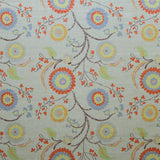 Printed fabric with a whimsical floral pattern in blue, yellow and orange with dark brown stems on a soft blue background. 