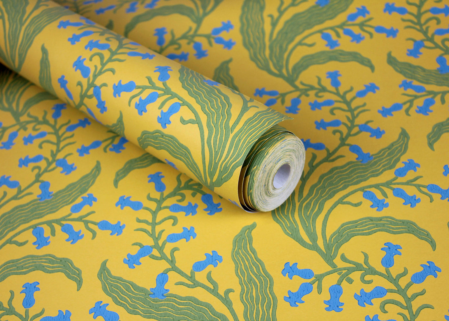 Wallpaper roll in a scrolling floral pattern in blue and green on a yellow field. 
