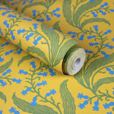 Wallpaper roll in a scrolling floral pattern in blue and green on a yellow field. 