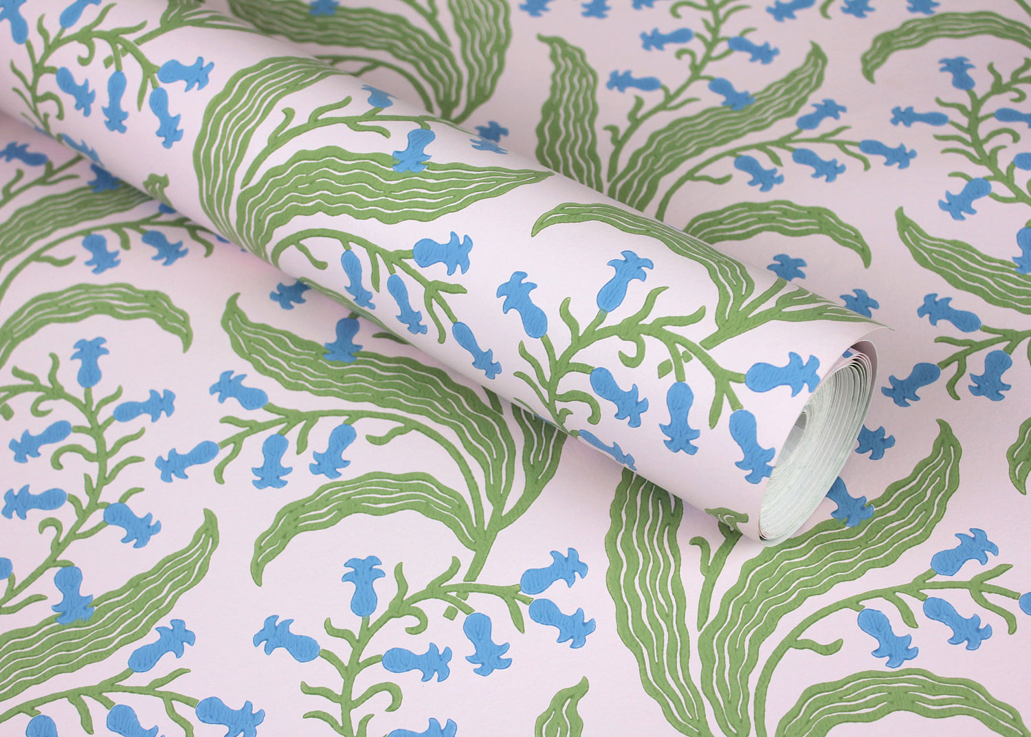 Wallpaper roll in a scrolling floral pattern in blue and green on a pink field. 