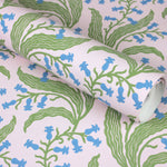 Wallpaper roll in a scrolling floral pattern in blue and green on a pink field. 