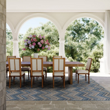 Outdoor dining room schene, with wooden table and chairs atop a blue and brown chevron area rug.