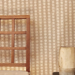 A wooden chair and ceramic vase against wallpaper in a circle and stripe print in white on a oatmeal field.