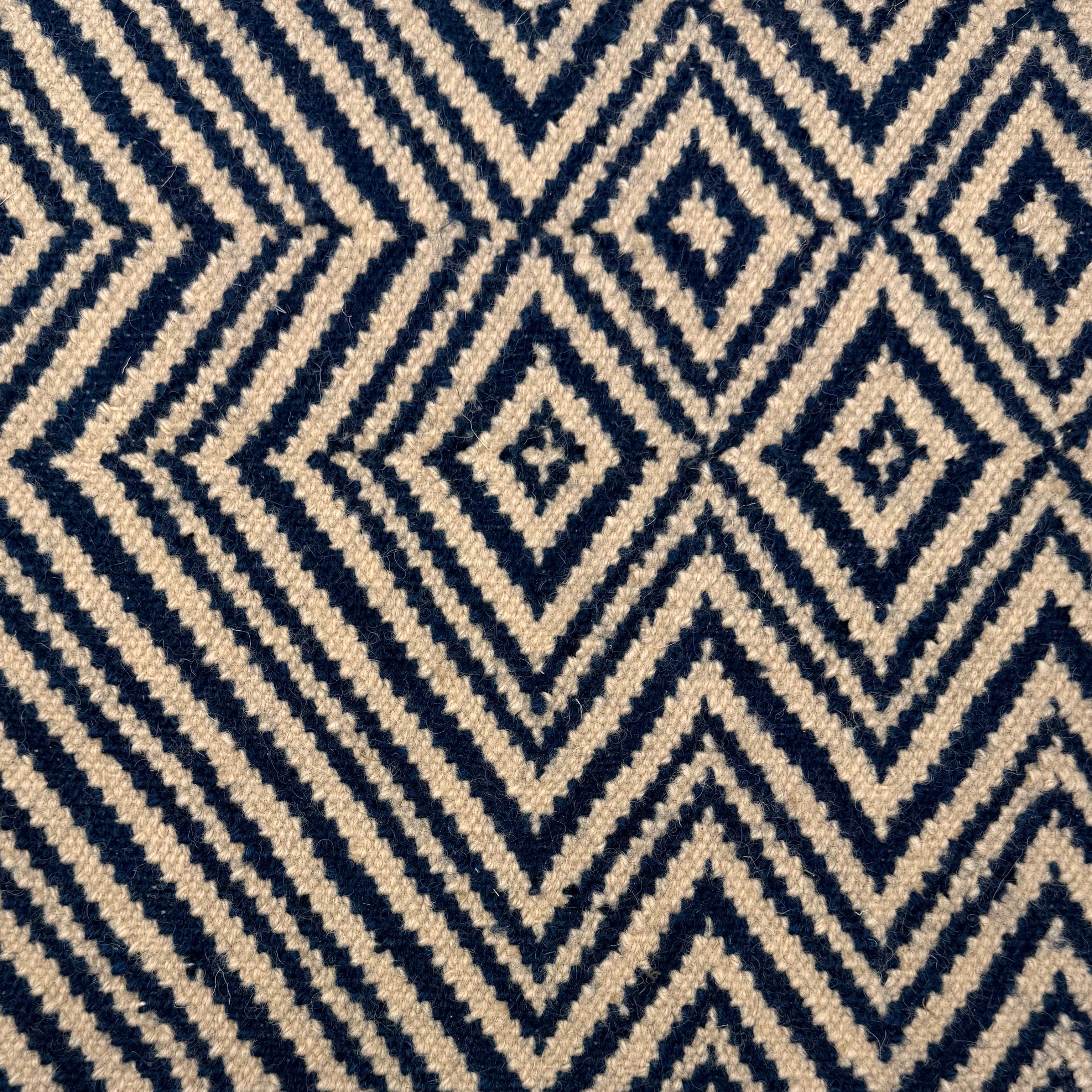 Handwoven rug in tan and navy blue in a diamond stripe design. 