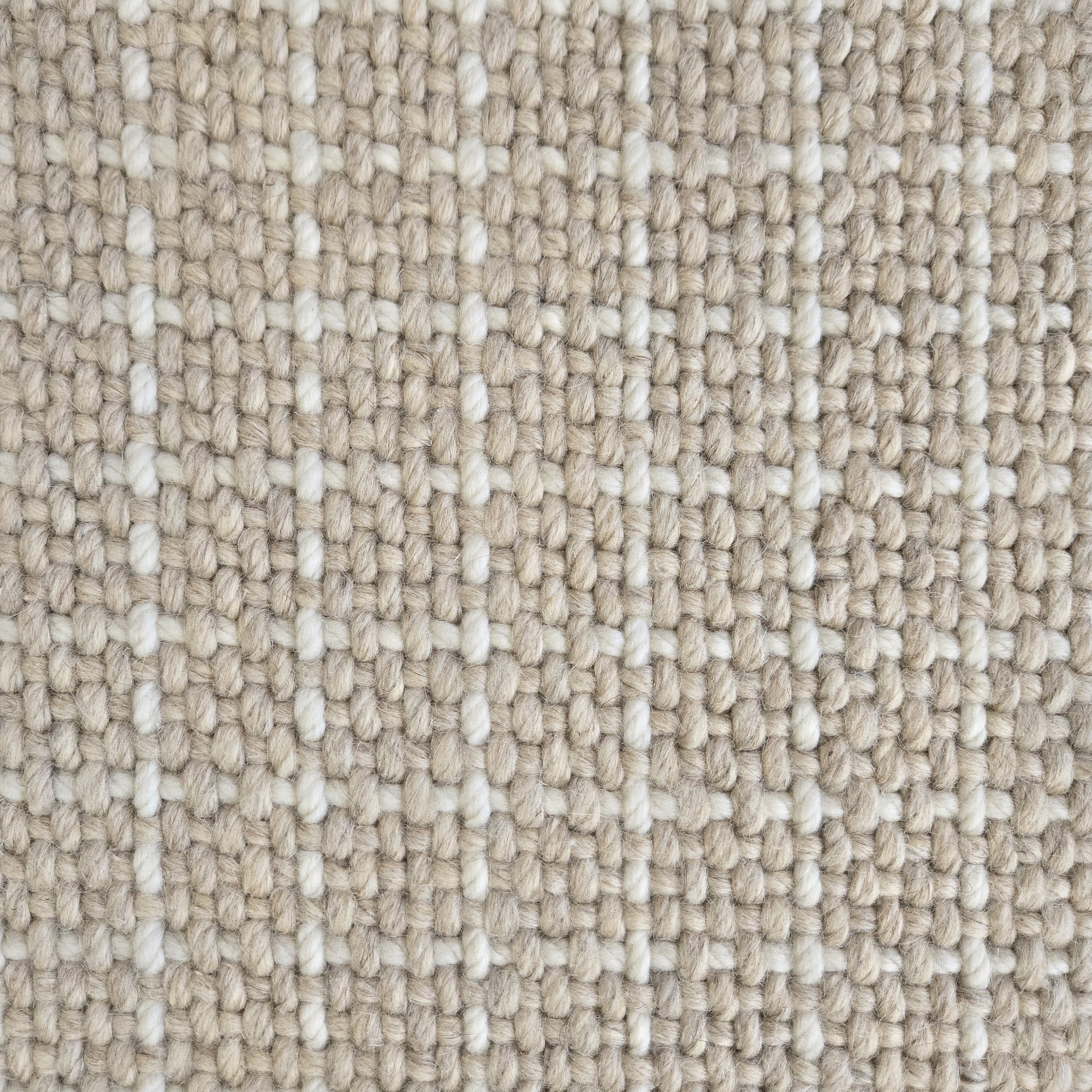 Close-up of a carpet with a textured check pattern in beige and cream. 