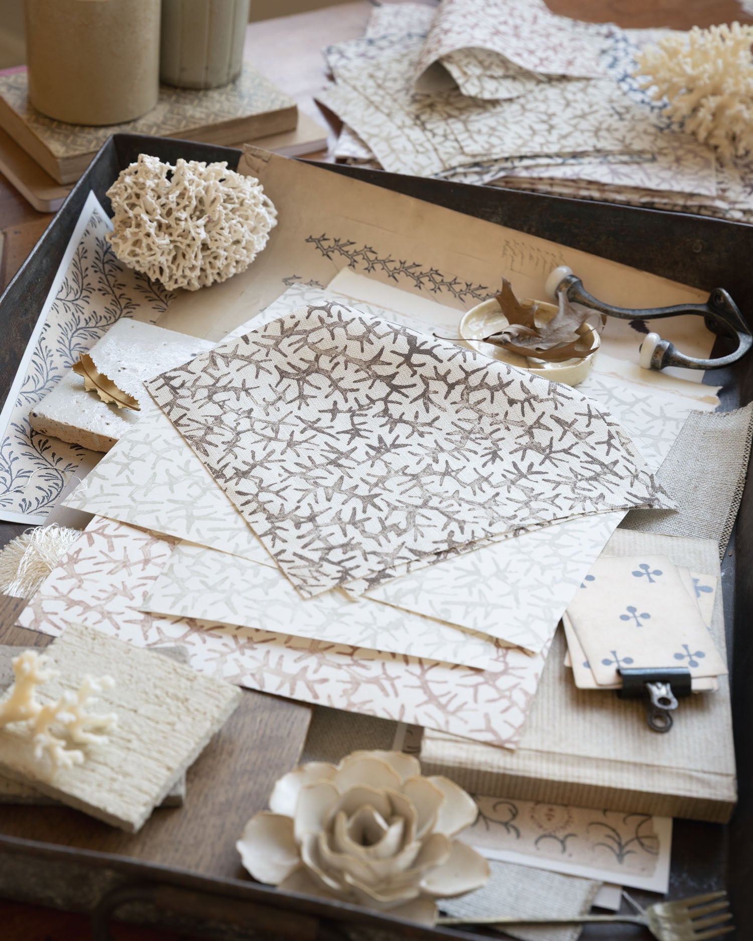 Desk scene with layered swatches of fabrics and natural specimens. 