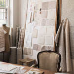 Studio desk setting with textile designs in progress featuring a coral watercolor pattern. 