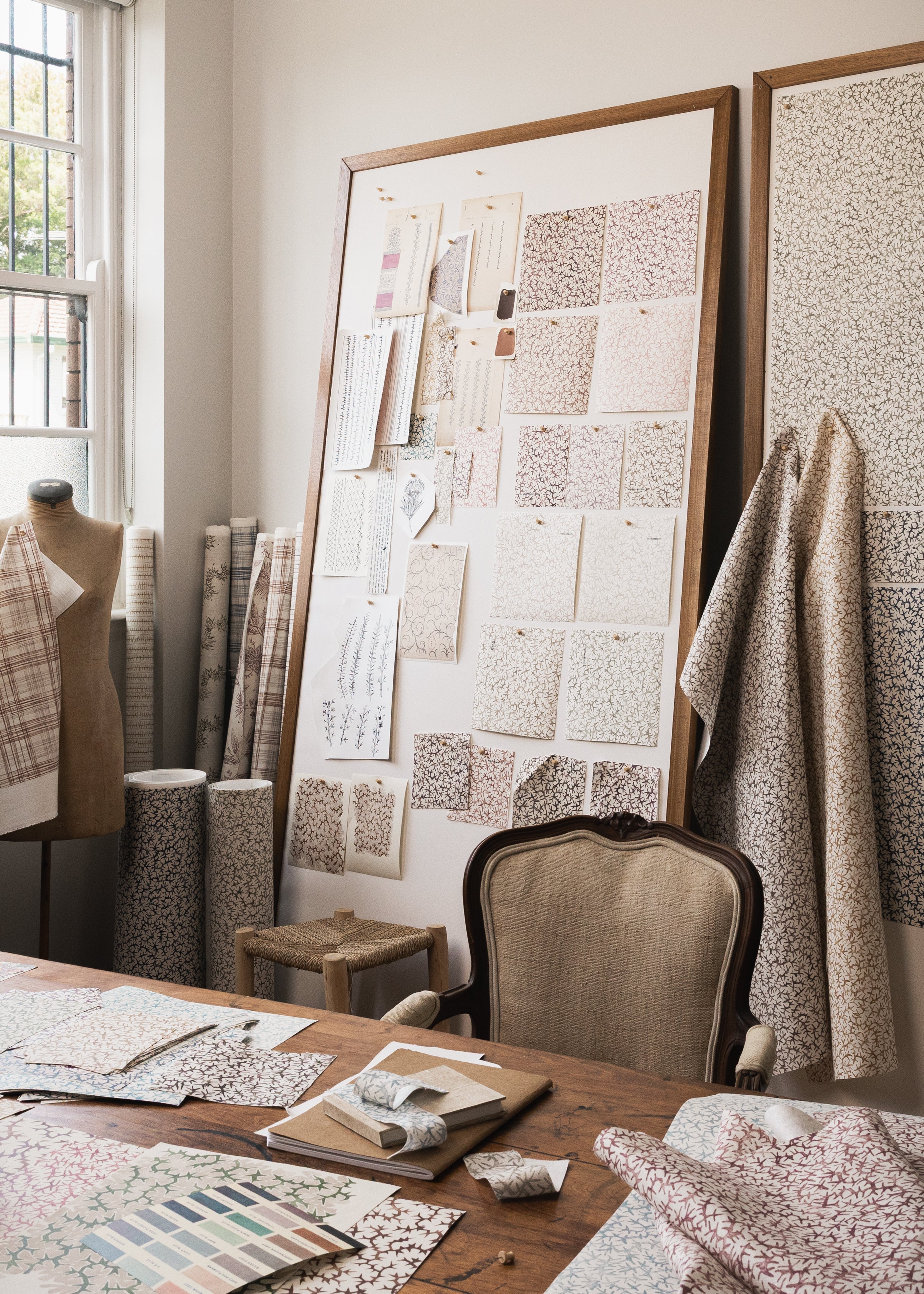 Studio desk setting with textile designs in progress featuring a coral watercolor pattern. 