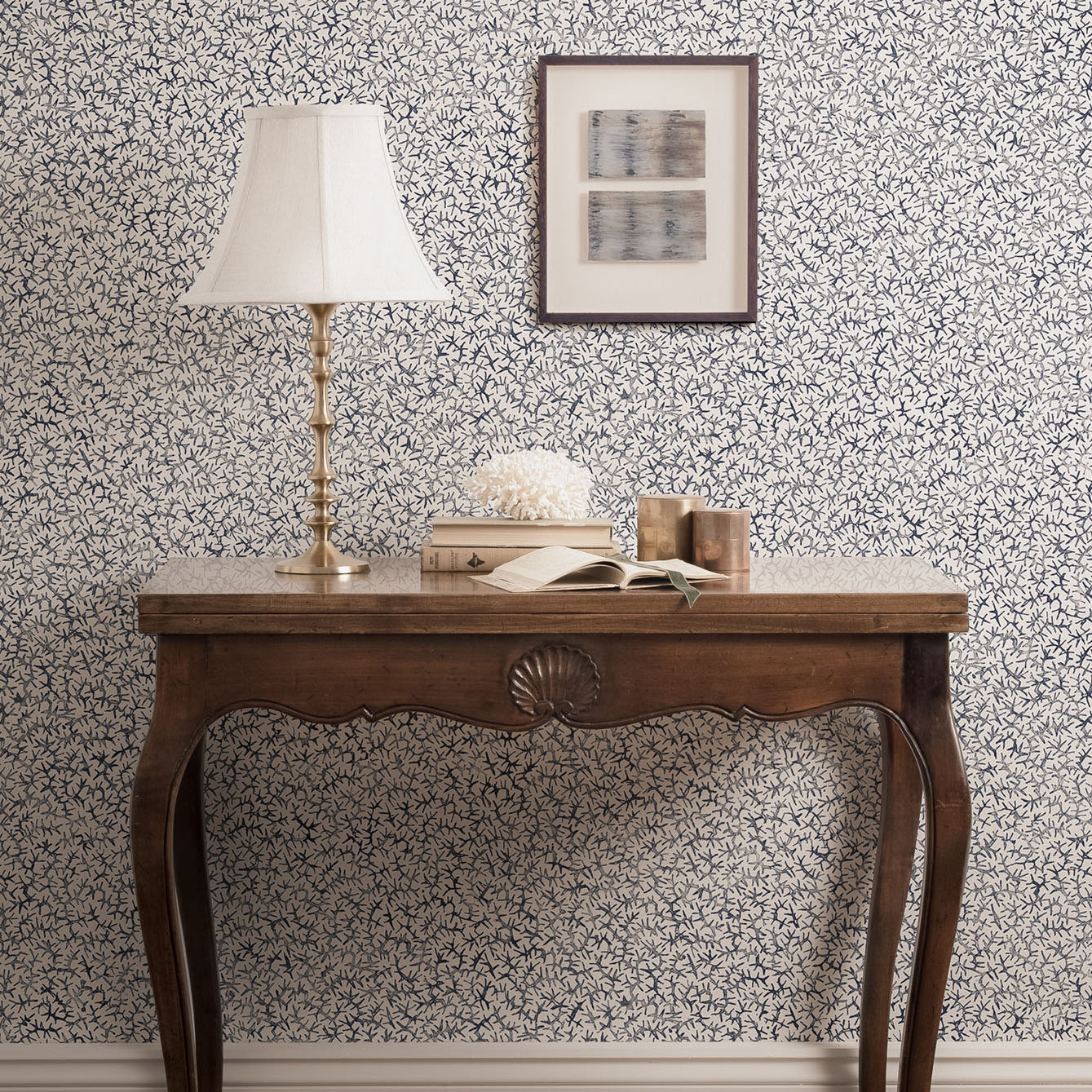 Wooden table with vintage accessories against a blue and white wallpaper wall. 