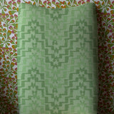 Upholstered dining chair in bold green stripe against floral wallpaper
