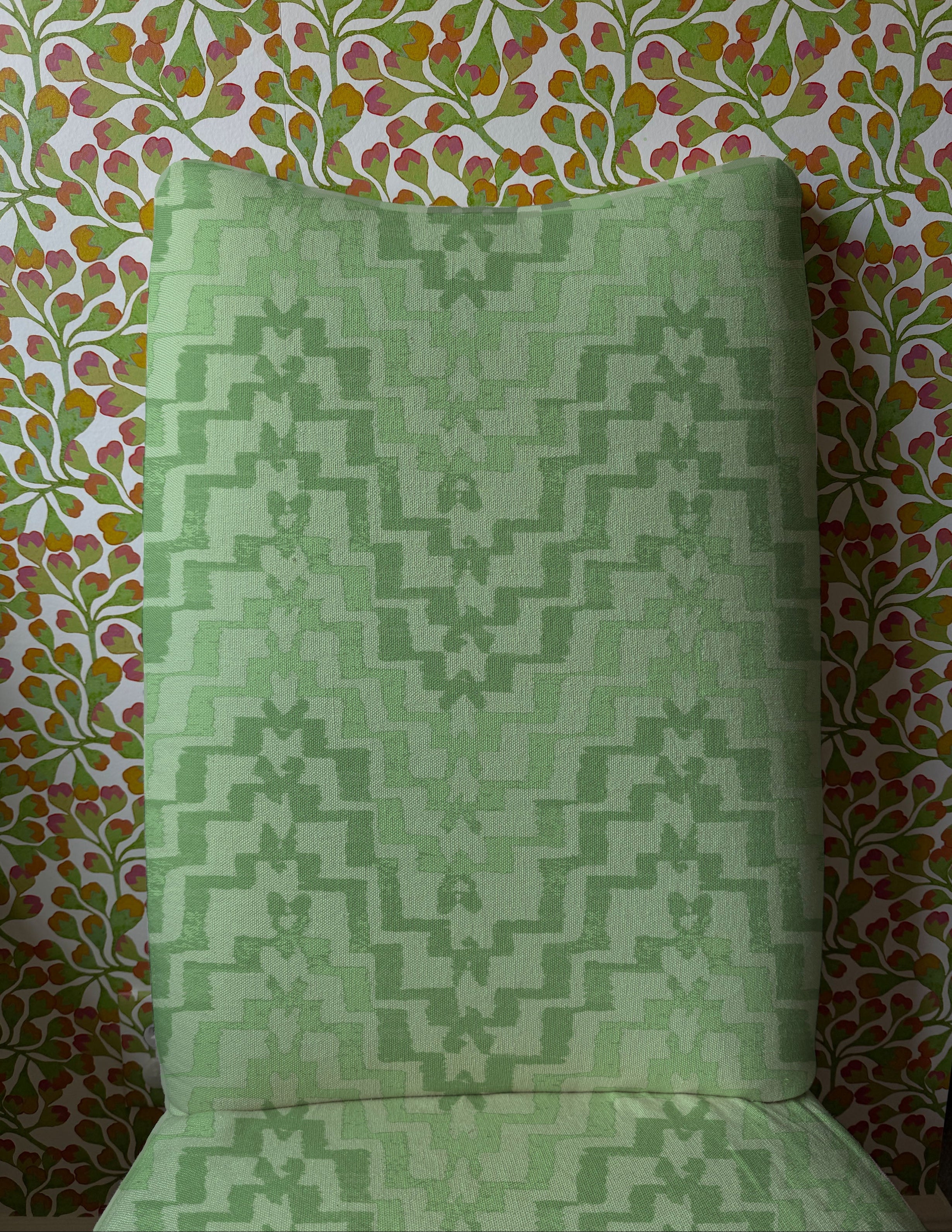 Upholstered dining chair in bold green stripe against floral wallpaper