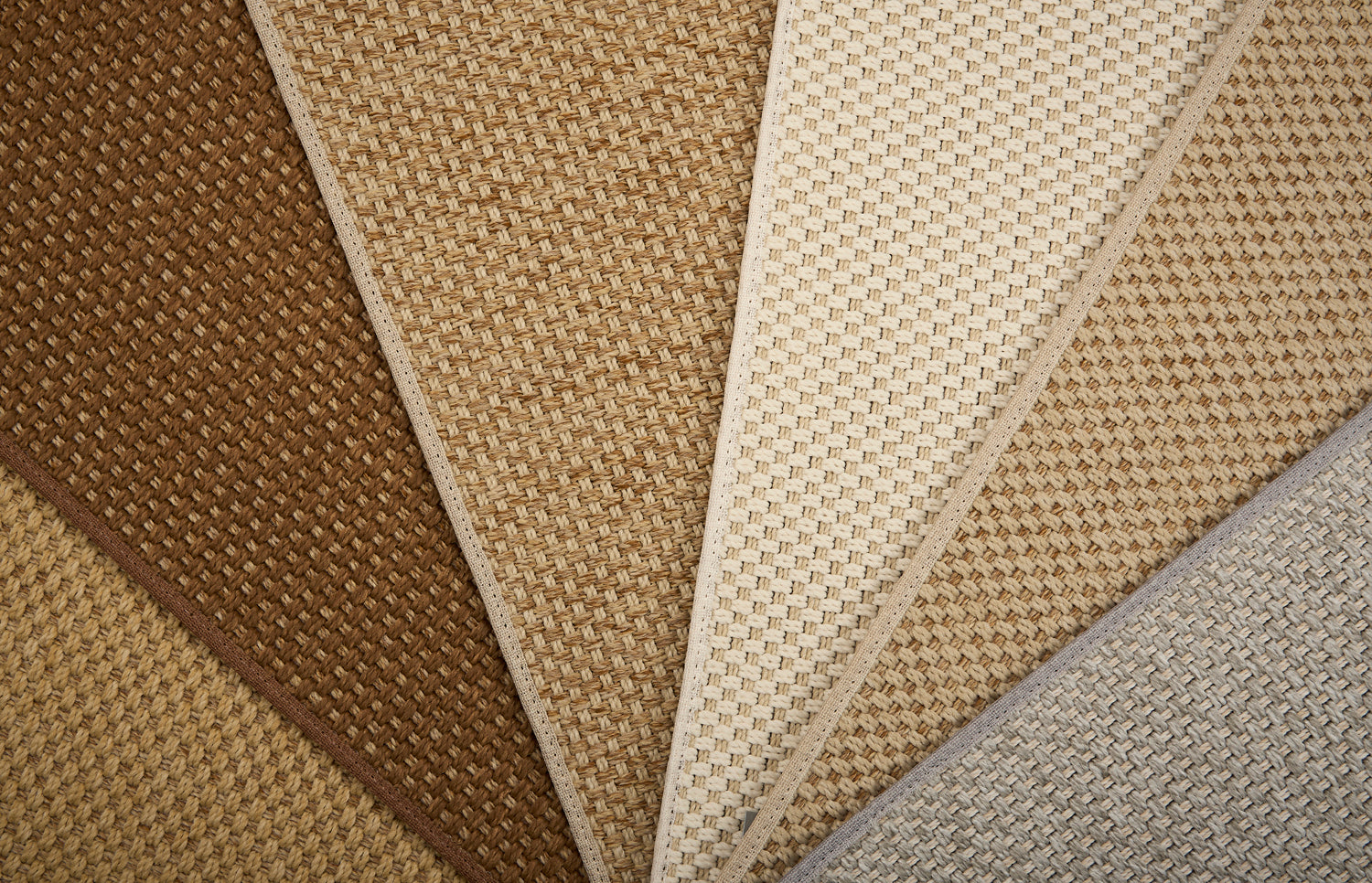 Close-up of broadloom carpet samples in brown, beige, and gray.
