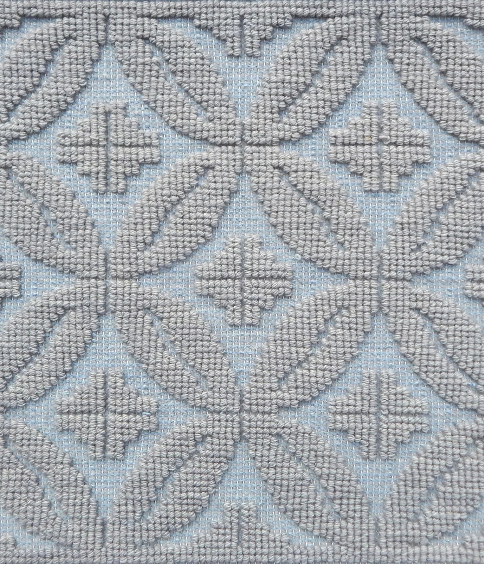 Handmade rug with classic circle lattice design in grey on a blue field. 