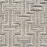 A close-up of a handwoven carpet with a repeating geometric maze in off white. 