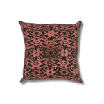 Square throw pillow in a repeating abstract block print pattern in mottled pink on a black field.