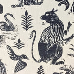 Close-up of fabric in a lion and plant print in navy on a mottled white field.