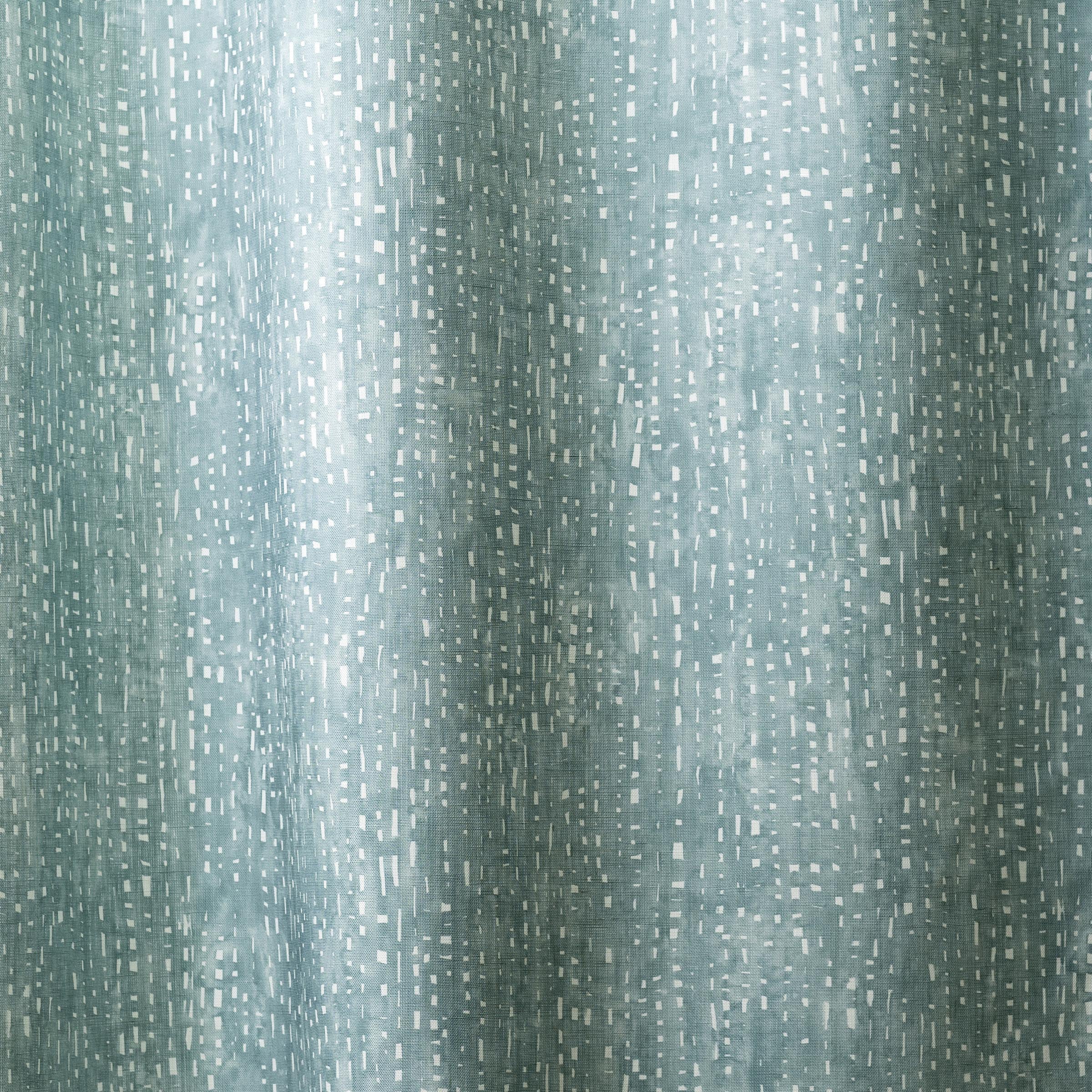 Draped linen in a painterly small-scale dashed dot print in white on a soft peacock blue watercolor field.