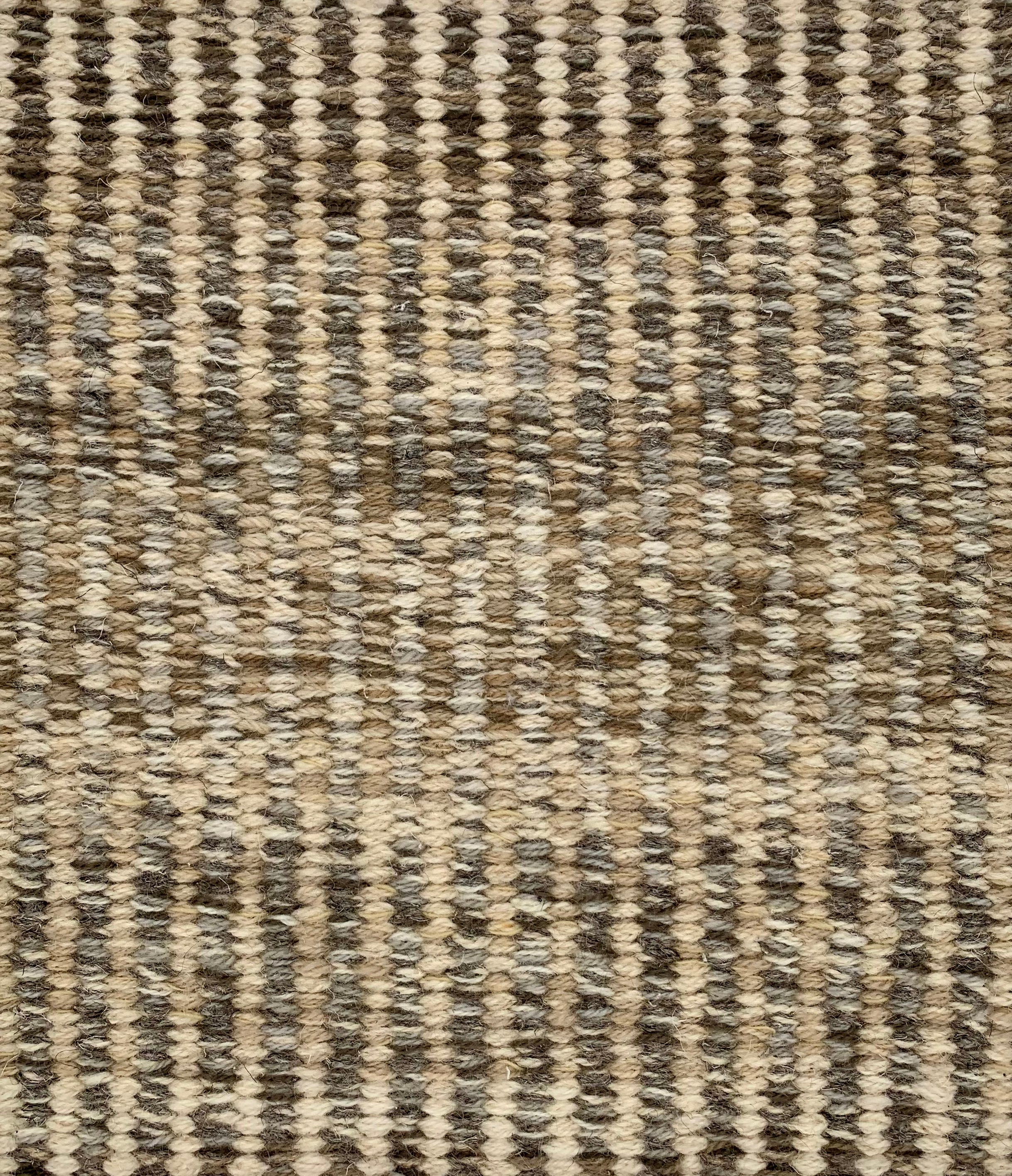 Handwoven rug detail in a textural design in beige, tan, and brown