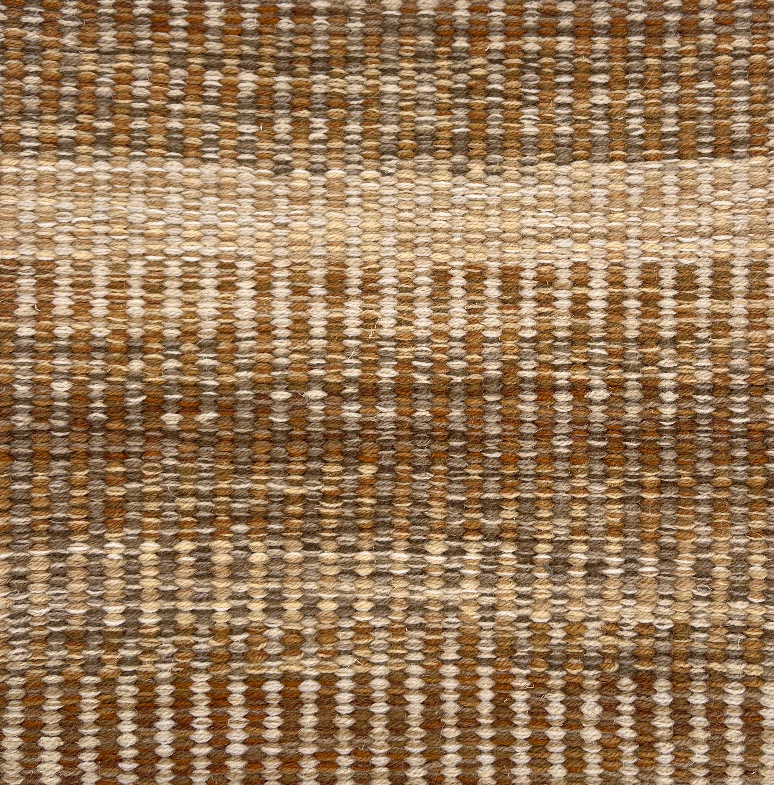 Handwoven rug detail in a textural stripe design in tan and beige