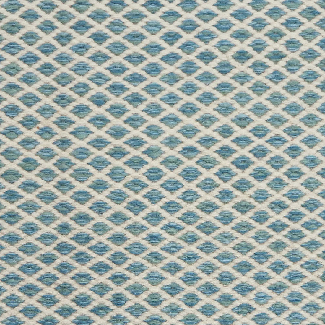 Handwoven rug with small scale diamond lattice in cream on a tan and marine blue field. 