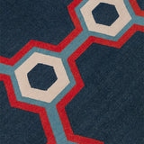 Detail of a flatwoven rug in a bold geometric floral-like design in blue, navy, red and cream. 