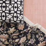 A close-up of floral and vine patterned fabric and decorative pillow with bold lattice design layered over a pink tonal striped wallpaper. 