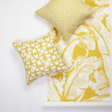 Two decorative throw pillows in yellow and white patterns, styled next to a matching yellow and white tropical banana leaf patterned wallpaper on a white background.