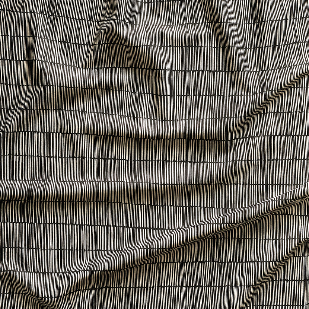 Close up of gently draped printed linen with thin hand drawn stripe grid in ivory on black.