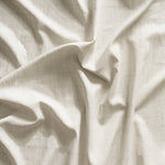 Close up of gently draped printed linen with thin hand drawn stripe grid in white on cream.